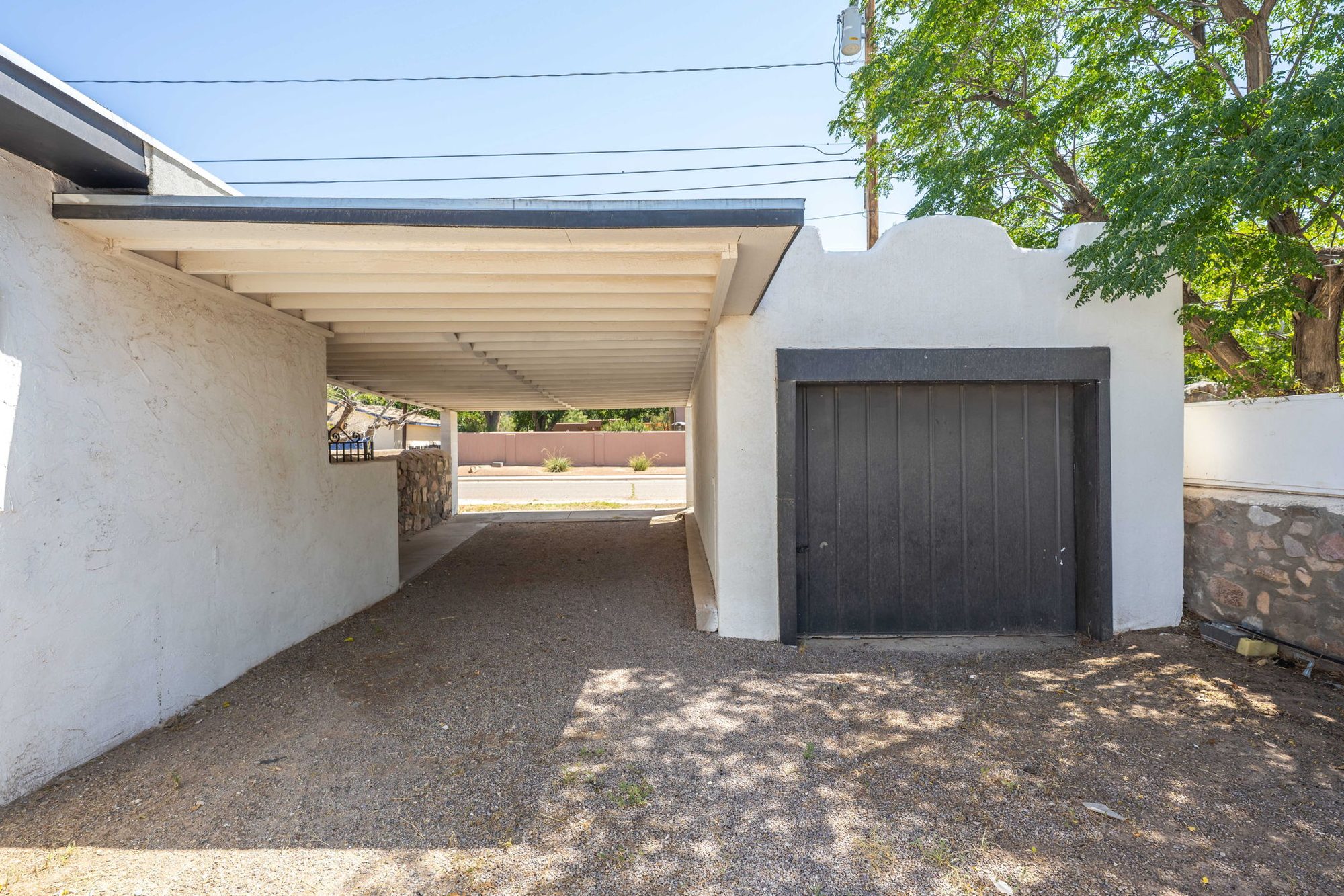Carport beside the detached garage with a scalloped adobe parapet