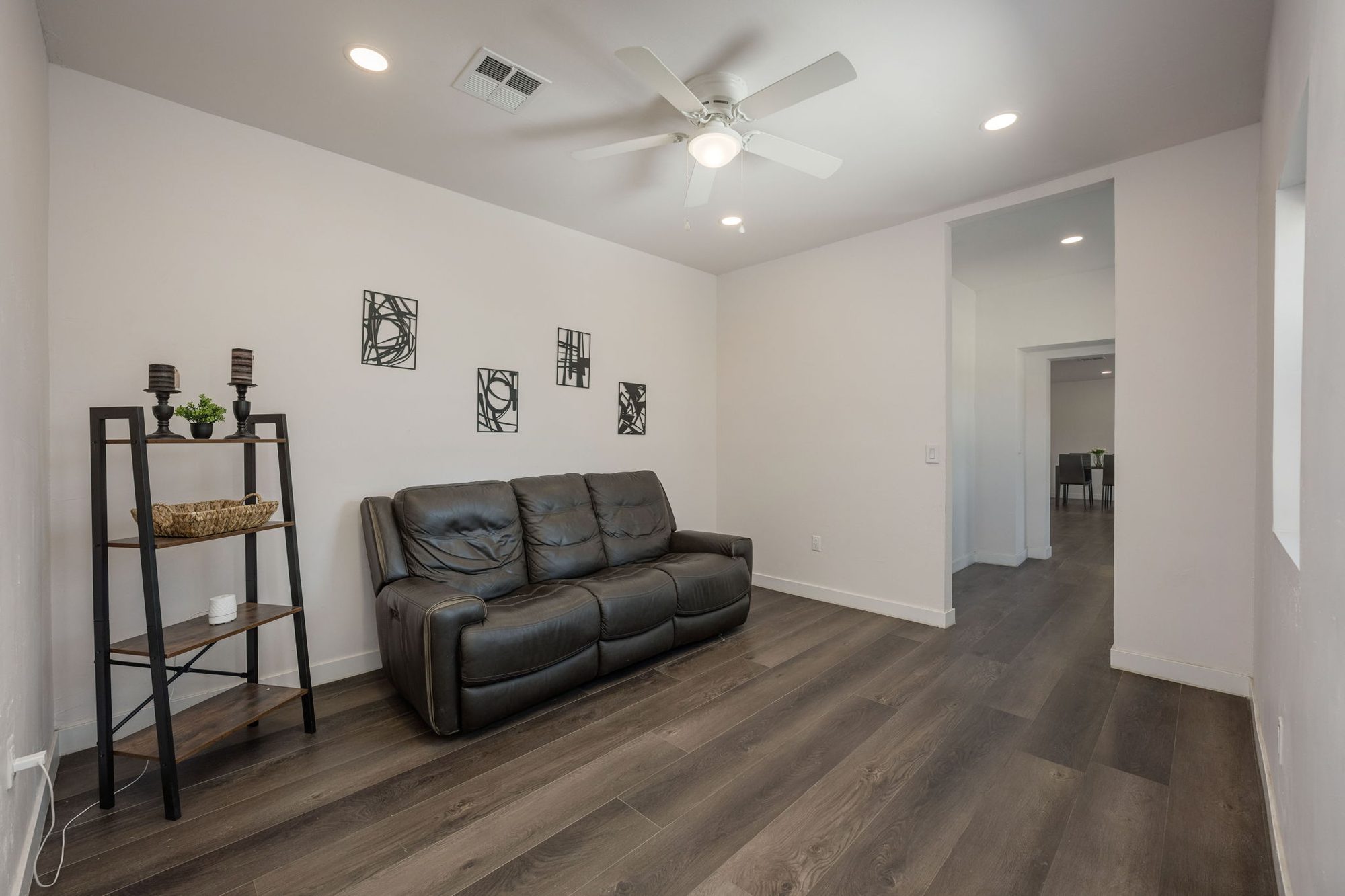 Family room with ceiling fan and wide-plank floors opening toward the dining room
