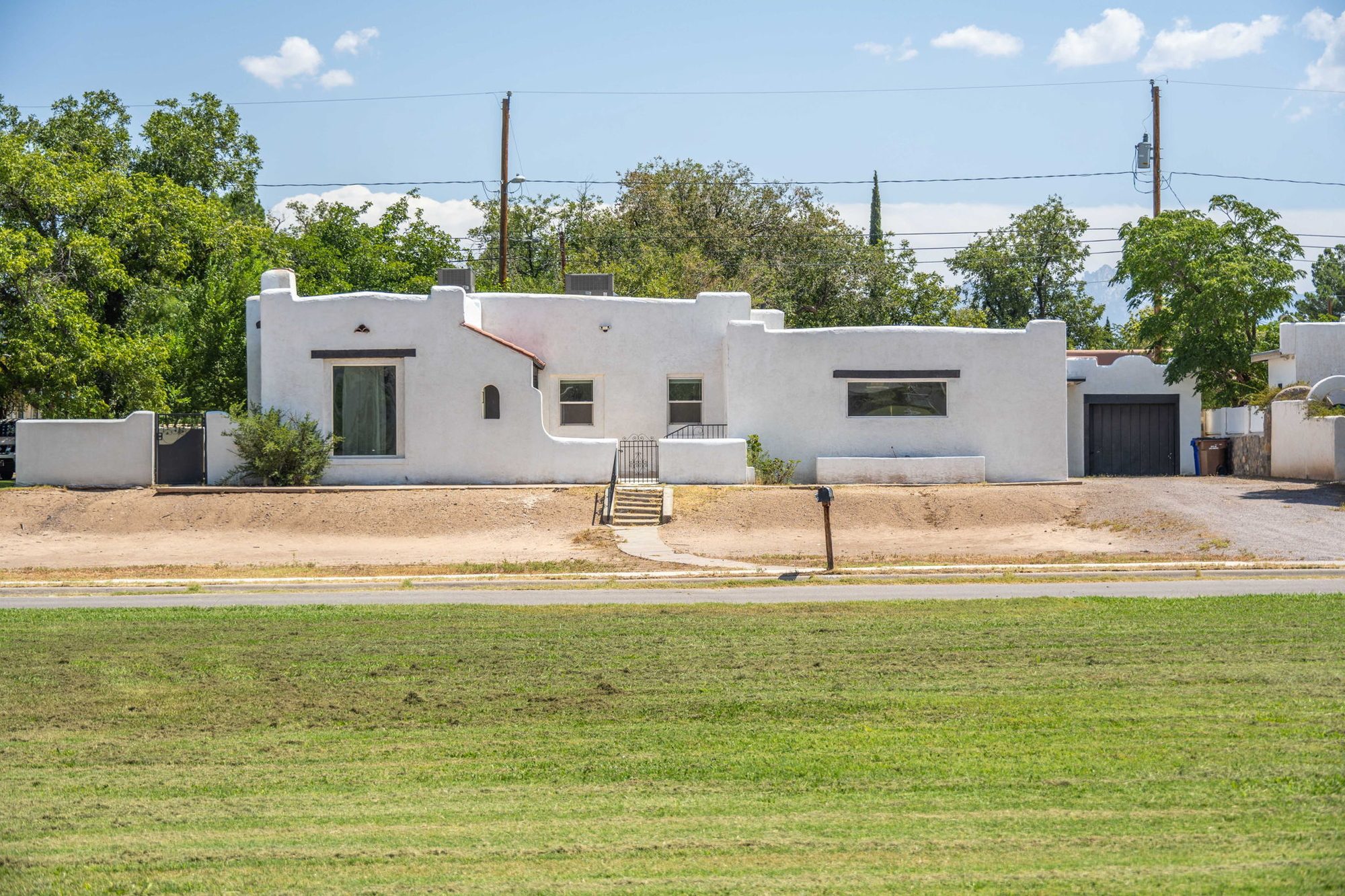 White adobe exterior seen from the city park across the street