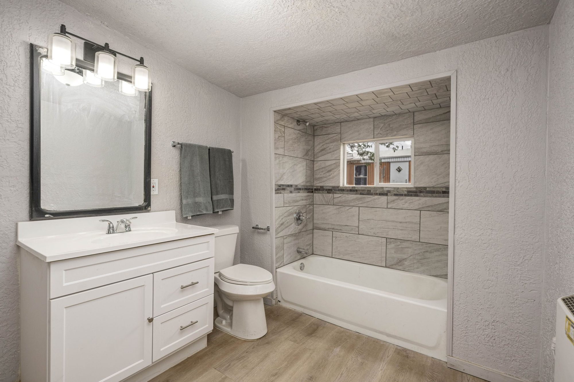 Updated full bath with tiled tub-and-shower surround and white vanity