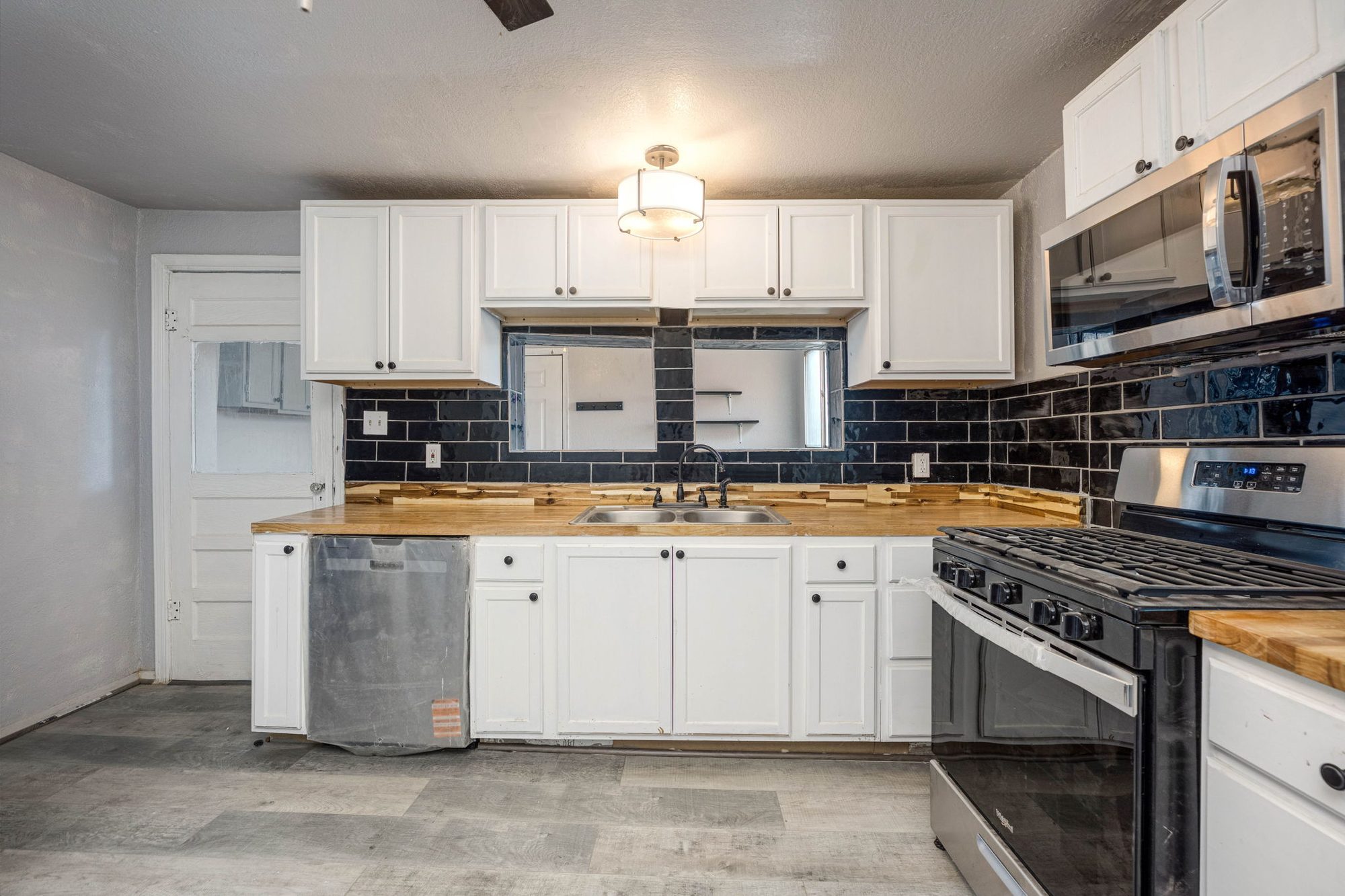 Reimagined kitchen with white cabinets, butcher-block counters, and stainless appliances