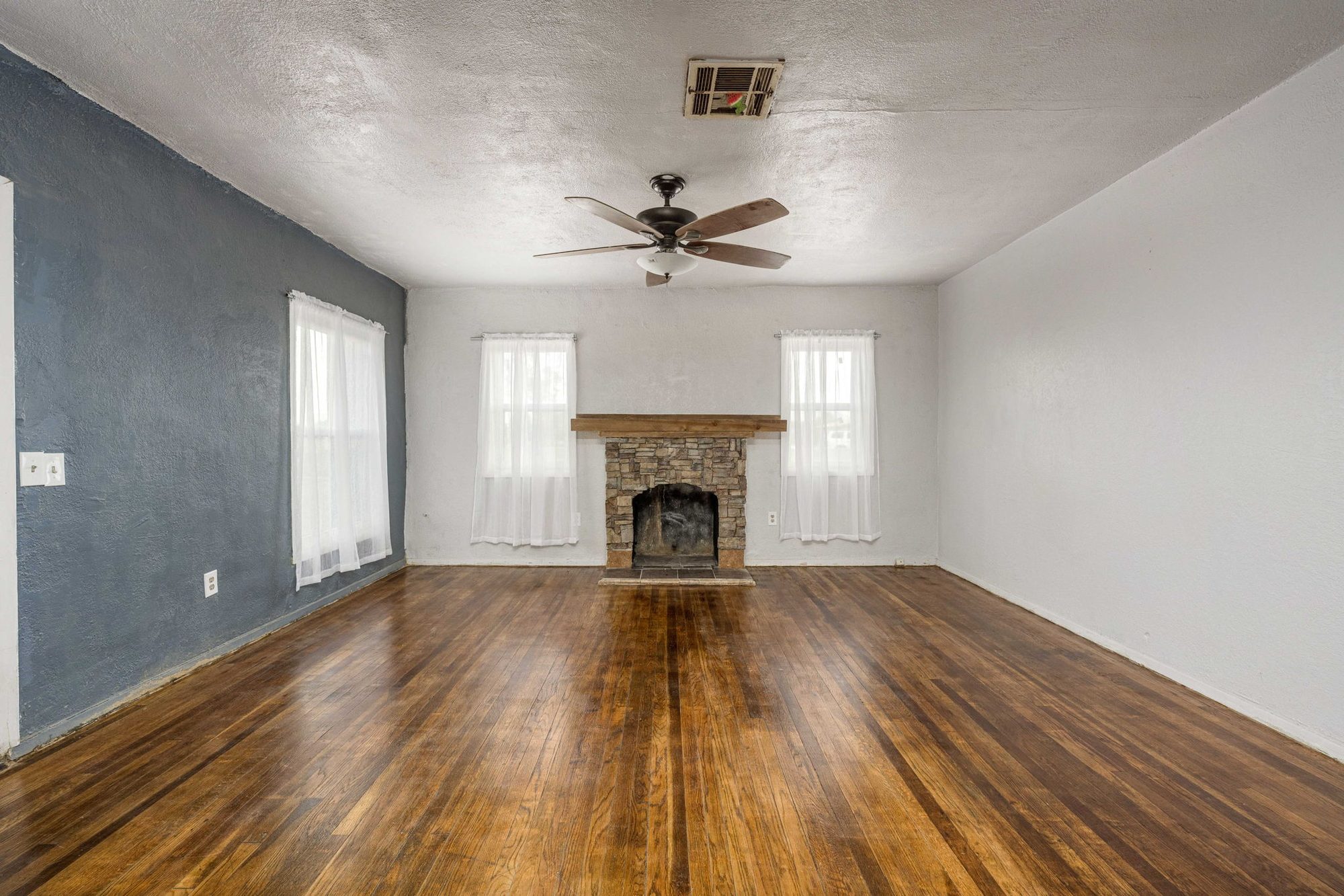 Living room with stone fireplace and refinished hardwood floors