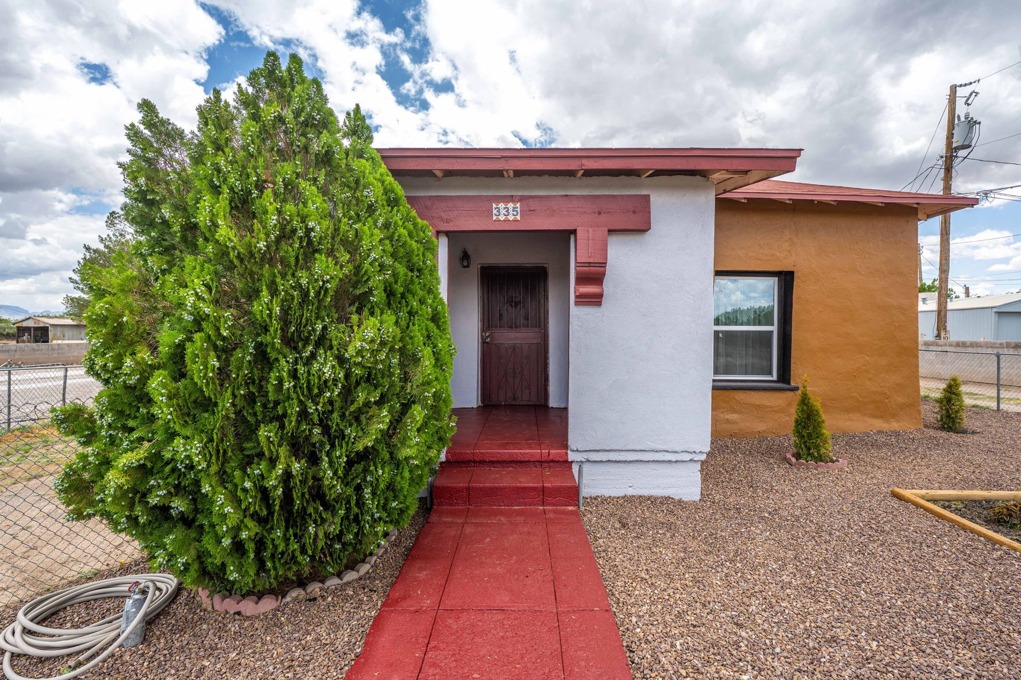 Covered front porch with red steps and house number 335
