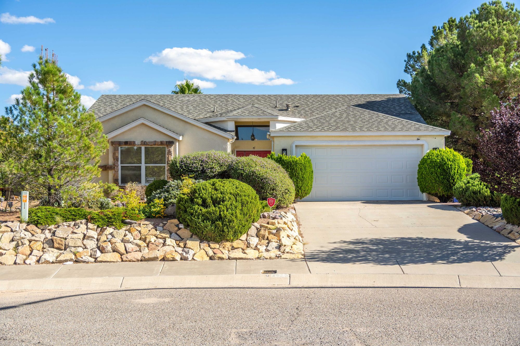 Front exterior with stone-terraced landscaping and two-car garage
