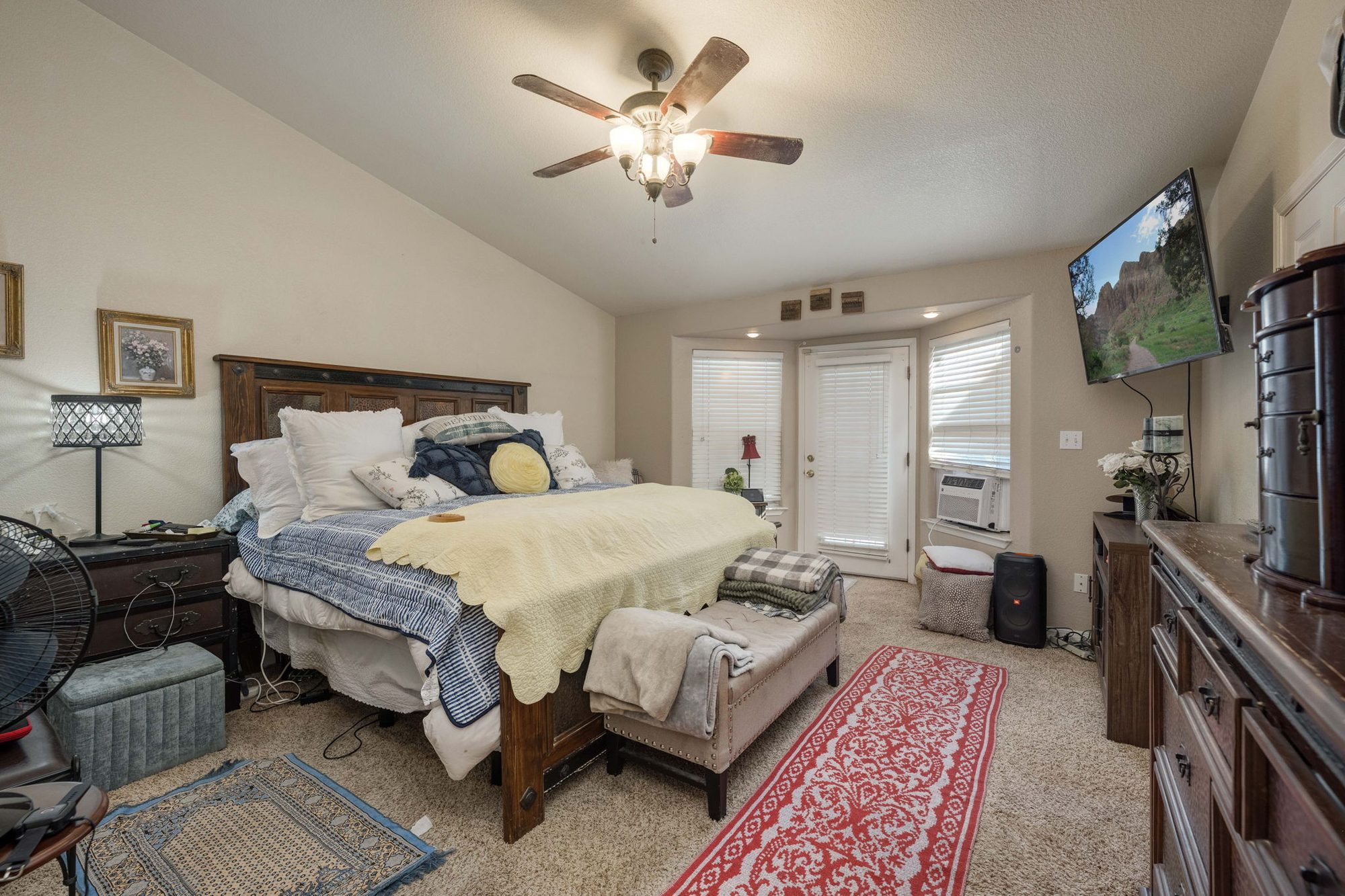 Primary bedroom with vaulted ceiling and backyard door