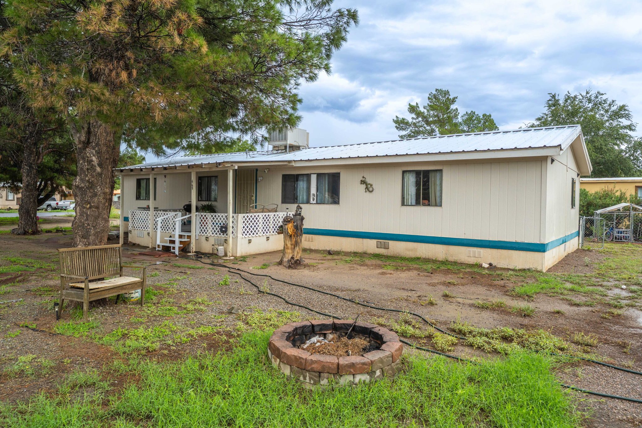 669 Hummingbird Drive with a metal roof and covered front deck under tall pines