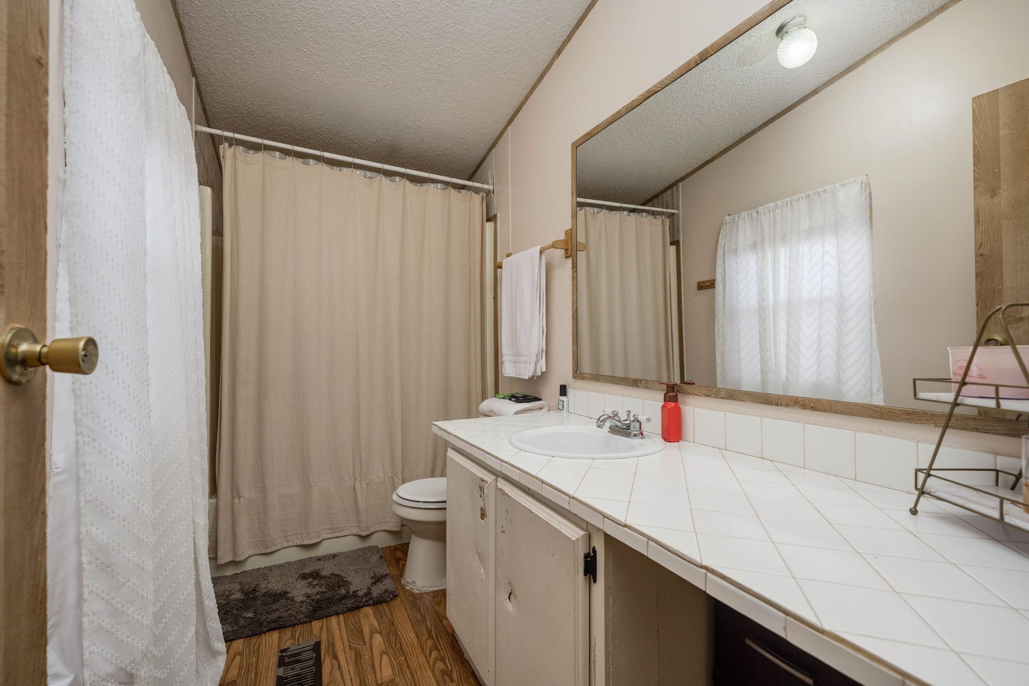 Primary bath with long tiled vanity and tub-shower combo